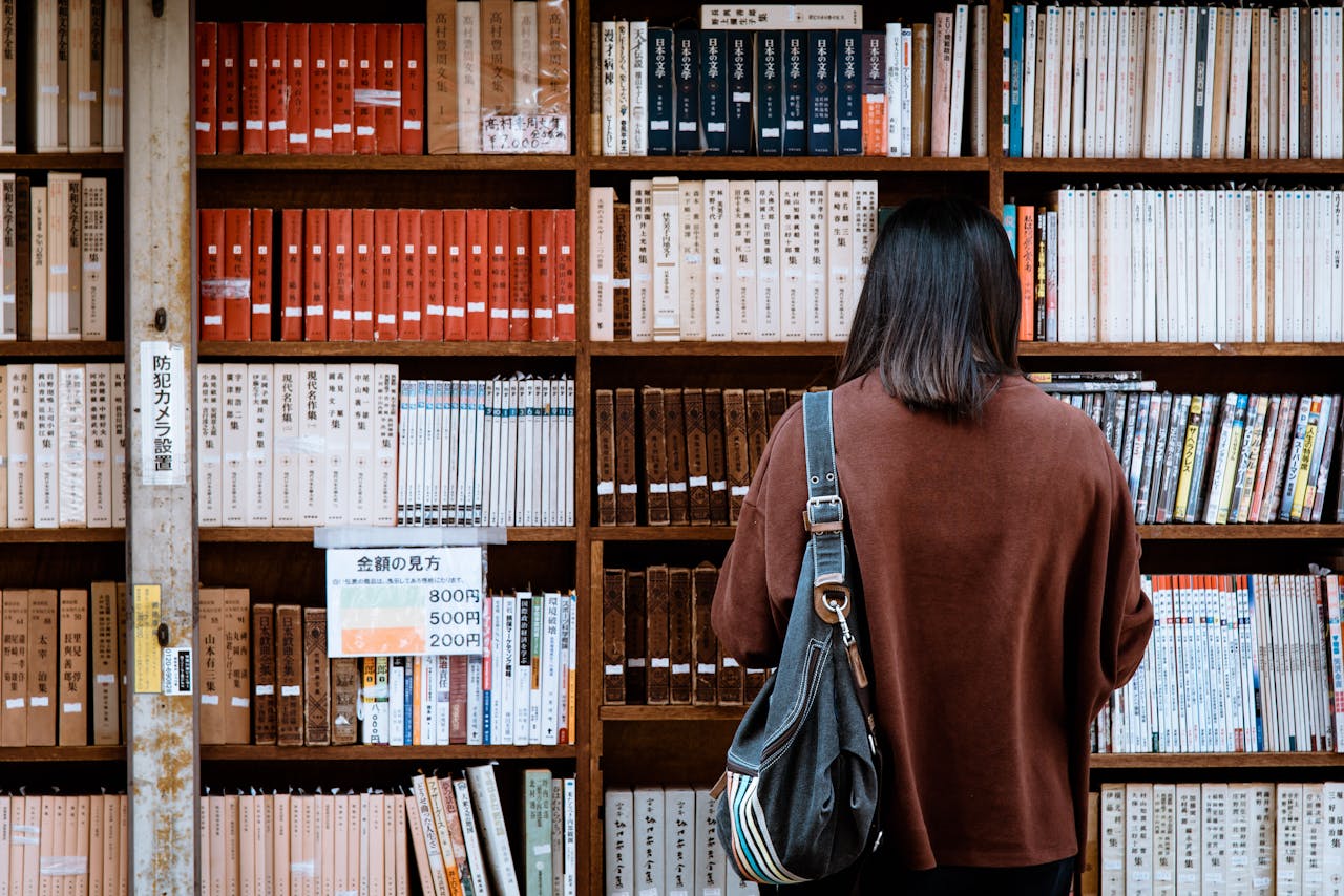 Woman browsing books at a library in Nagano, Japan. Explore knowledge and literature.